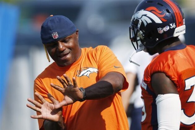 Denver Broncos defensive backs coach Joe Woods, left, gestures while speaking to cornerback Kayvon Webster during the team's NFL football training camp session early Thursday, Aug. 20, 2015, in Englewood, Colo. (AP Photo/David Zalubowski)