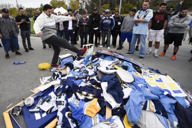 Chris Githens, left, kicks a pile of Chargers memorabilia in front of San Diego Chargers headquarters after the team announced that it will move to Los Angeles Thursday Jan. 12, 2017, in San Diego. (AP Photo/Denis Poroy)