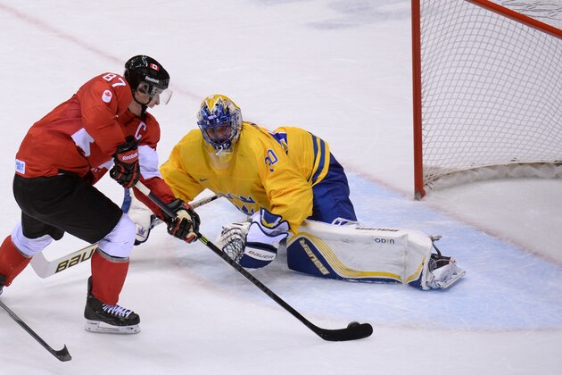 Canada's Sidney Crosby scores in the nets of Sweden's goalkeeper Henrik Lundqvist during the Men's ice hockey final Sweden vs Canada at the Bolshoy Ice Dome during the Sochi Winter Olympics on February 23, 2014. AFP PHOTO / YURI KADOBNOV        (Photo credit should read YURI KADOBNOV/AFP/Getty Images)