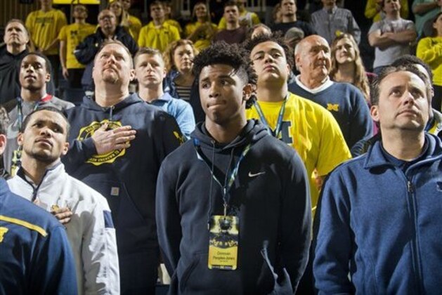 Detroit Cass Tech junior wide receiver Donovan Peoples-Jones, center, stand next to Michigan wide receivers coach Jedd Fisch, right, and other fellow recruits and Michigan football coaches at an NCAA college basketball game against Northwestern at Crisler Center in Ann Arbor, Mich., Wednesday, Feb. 24, 2016. Peoples-Jones is on an unofficial recruiting visit after receiving an offer to play for Michigan. (AP Photo/Tony Ding)