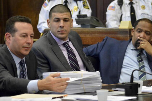Former New England Patriots football player Aaron Hernandez, center, and defense attorney Ronald Sullivan watch as lead attorney Jose Baez presents a stack of discovery documents as the reason for requesting a continuance in Hernandez' upcoming double murder trial. (Chris Christo /The Boston Herald via AP, Pool)