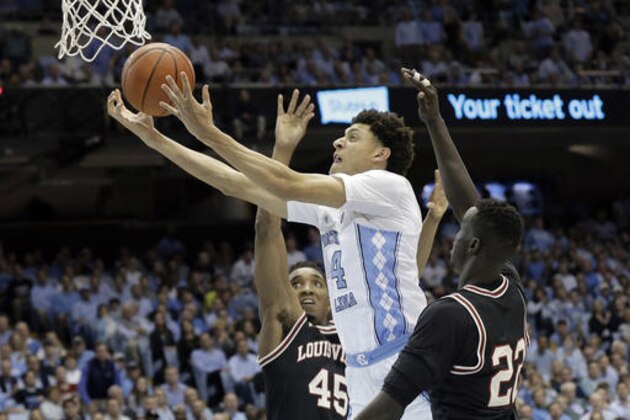 North Carolina's Justin Jackson (44) drives between Louisville's Donovan Mitchell (45) and Deng Adel (22) during the first half of an NCAA college basketball game in Chapel Hill, N.C., Wednesday, Feb. 22, 2017. (AP Photo/Gerry Broome)