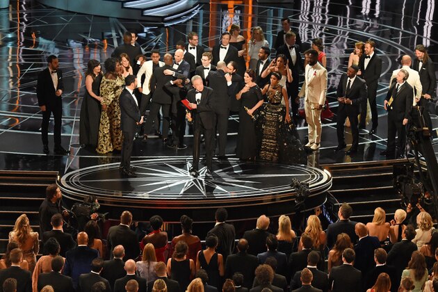 The cast of 'Moonlight' and ''La La Land' appear on stage as presenter Warren Beatty (C), flanked by host Jimmy Kimmel (L) shows the winner's envelope for Best Movie 'Moonlight' on stage at the 89th Oscars on February 26, 2017 in Hollywood, California. / AFP / Mark RALSTON        (Photo credit should read MARK RALSTON/AFP/Getty Images)