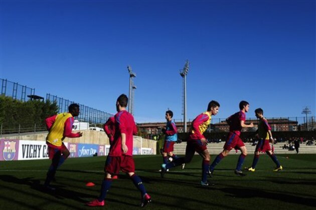 FILE - In this Jan. 8, 2011 file photo, Barcelona youth players from 'La Masia' football academy warm up at the Barcelona FC's Joan Gamper training camp in San Joan Despi, Spain. The Court of Arbitration for Sport on Tuesday Dec. 30, 2014 dismissed Barcelona's appeal and upheld the transfer ban FIFA imposed on the club for infringing regulations on registering minors as youth players. CAS said in a statement that “Barcelona had breached the rules regarding the protection of minors and the registration of minors attending football academies.” The ruling means Barcelona will be barred from signing any players in 2015. Barcelona is renowned for training and educating young players such as Lionel Messi and Andres Iniesta at it's La Masia academy, in the hope they develop the talent to graduate to the senior team. (AP Photo/Manu Fernandez, File)