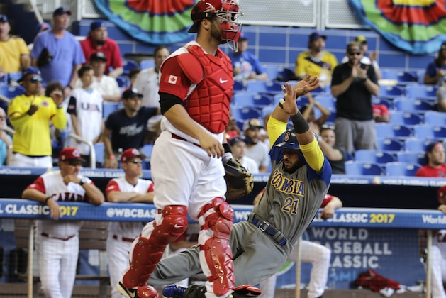 Colombia's Jhonatan Solano (21) slides past Canada catcher George Kottaras to score on an RBI single by Donovan Solano during the third inning of a first-round game in the World Baseball Classic, Saturday, March 11, 2017, in Miami. (AP Photo/Lynne Sladky)