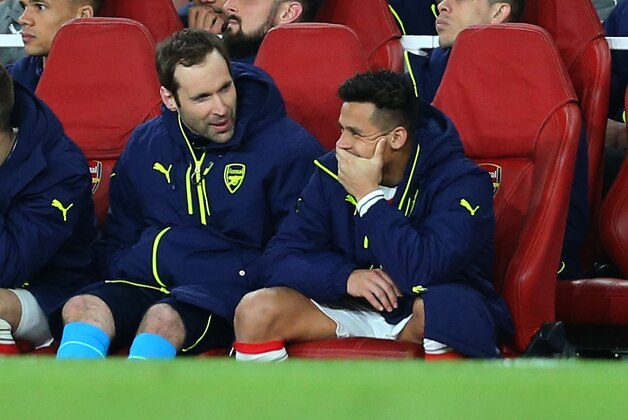 LONDON, ENGLAND - MARCH 07: Alexis Sanchez  appears to smirk as he, Aaron Ramsey and Petr Cech of Arsenal watch from the bench during the UEFA Champions League Round of 16 second leg match between Arsenal FC and FC Bayern Muenchen at Emirates Stadium on March 7, 2017 in London, United Kingdom. (Photo by Catherine Ivill - AMA/Getty Images)