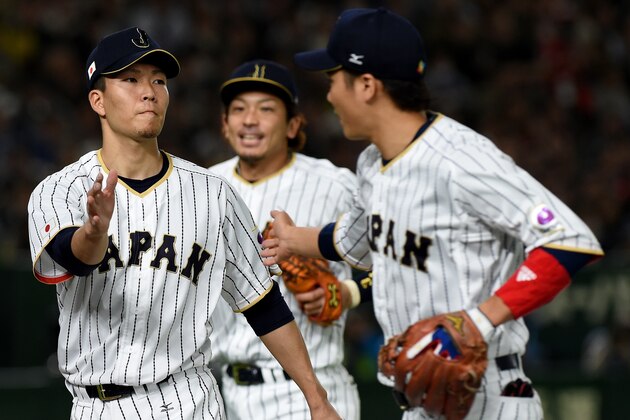 Japanese starter Kodai Senga (L) is congratulated by his teamates after the top of the first inning during the World Baseball Classic Pool E second round match between Israel and Japan at Tokyo Dome in Tokyo on March 15, 2017. / AFP PHOTO / TORU YAMANAKA        (Photo credit should read TORU YAMANAKA/AFP/Getty Images)