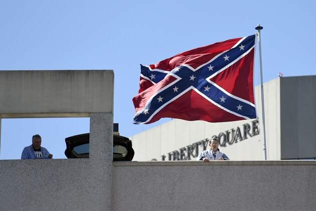 Basketball fans look out as a Confederate flag flies from a parking deck outside the arena before a second-round game of the NCAA men's college basketball tournament in Greenville, S.C., Sunday, March 19, 2017. A small group of protesters flew a large Confederate flag from the top of a parking garage next to the arena hosting two men's NCAA Tournament games. (AP Photo/Rainier Ehrhardt)