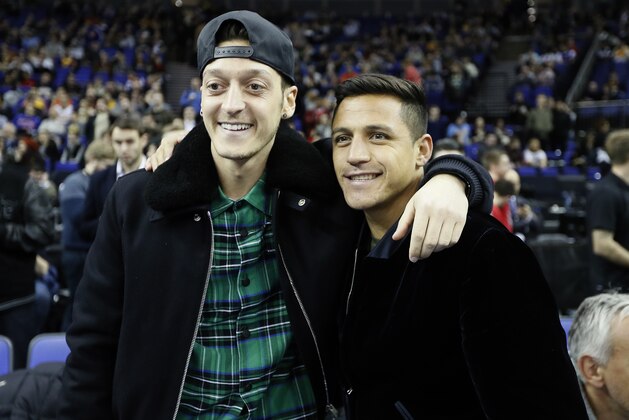 Arsenal soccer players Mesut Ozil, left, and Alexis Sanchez watch the NBA basketball match between Indiana Pacers and Denver Nuggets in London, Thursday, Jan. 12, 2017.(AP Photo/Kirsty Wigglesworth)