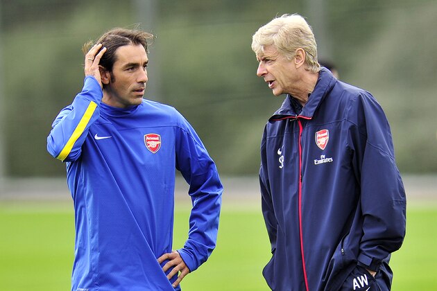 Arsenal's French manager Arsene Wenger (R) speaks with former Arsenal footballer Robert Pires during a team training session for the forthcoming UEFA Champions League Group F football match against SSC Napoli at Arsenal's London Colney training ground in north London on September 30, 2013. Arsenal will play against Napoli at the Emirates Stadium on October 1, 2013. AFP PHOTO/GLYN KIRK        (Photo credit should read GLYN KIRK/AFP/Getty Images)