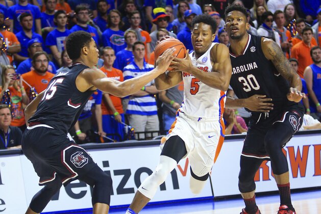 Florida guard KeVaughn Allen (5) drives to the basket between South Carolina guard PJ Dozier (15) and forward Chris Silva (30) during the first half of an NCAA college basketball game Tuesday, Feb. 21, 2017, in Gainesville, Fla. Florida won 81-66. (AP Photo/Matt Stamey)