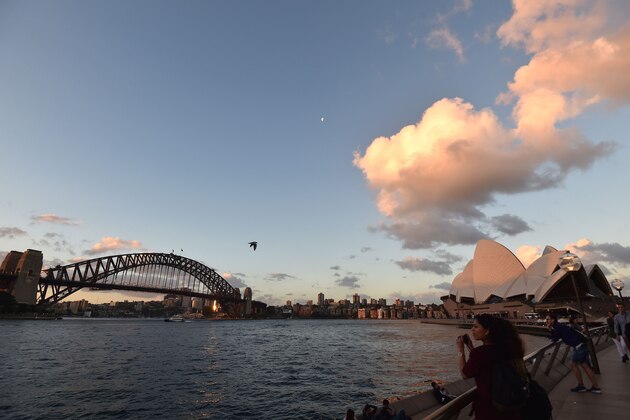 This picture taken on March 6, 2017 shows tourists taking pictures during sunset over Sydney's iconic landmark Opera House.  / AFP PHOTO / SAEED KHAN        (Photo credit should read SAEED KHAN/AFP/Getty Images)