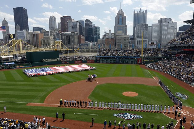 The Pittsburgh Pirates line the third base foul line as the Detroit Tigers line up on first base side as long-time Pirates season ticket holders unfurl a large American flag in center field during the playing of the national anthem before the Pirates home opener baseball game, Monday, April 13, 2015, in Pittsburgh. (AP Photo/Keith Srakocic)