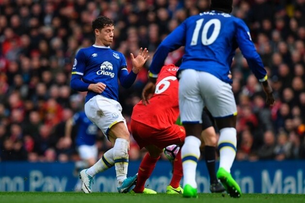 Liverpool's Croatian defender Dejan Lovren (C) is fouled by Everton's English midfielder Ross Barkley (L), who was subsequently booked during the English Premier League football match between Liverpool and Everton at Anfield in Liverpool, north west England on April 1, 2017. / AFP PHOTO / Paul ELLIS / RESTRICTED TO EDITORIAL USE. No use with unauthorized audio, video, data, fixture lists, club/league logos or 'live' services. Online in-match use limited to 75 images, no video emulation. No use in betting, games or single club/league/player publications.  /         (Photo credit should read PAUL ELLIS/AFP/Getty Images)
