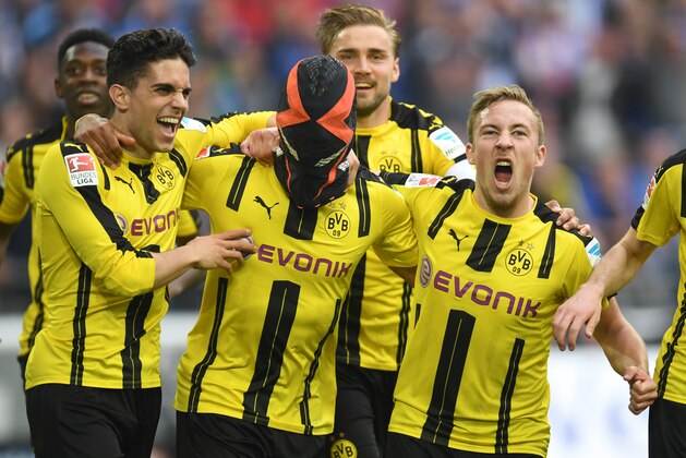 TOPSHOT - Dortmund's Gabonese striker Pierre-Emerick Aubameyang (C) wears a mask as he celebrates with his teammates Dortmund's after scoring the 0-1 during the German first division Bundesliga football match between FC Schalke 04 and Borussia Dortmund in Gelsenkirchen, western Germany, on April 1, 2017. / AFP PHOTO / PATRIK STOLLARZ / RESTRICTIONS: DURING MATCH TIME: DFL RULES TO LIMIT THE ONLINE USAGE TO 15 PICTURES PER MATCH AND FORBID IMAGE SEQUENCES TO SIMULATE VIDEO. == RESTRICTED TO EDITORIAL USE == FOR FURTHER QUERIES PLEASE CONTACT DFL DIRECTLY AT + 49 69 650050
        (Photo credit should read PATRIK STOLLARZ/AFP/Getty Images)