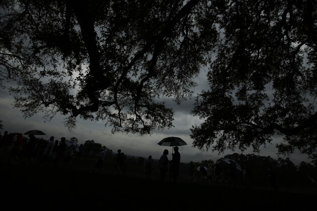 Fans stand under a tree during the par three competition at the Masters golf tournament Wednesday, April 5, 2017, in Augusta, Ga. (AP Photo/Charlie Riedel)