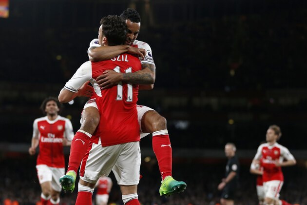Arsenal's English midfielder Theo Walcott (up) celebrates with Arsenal's German midfielder Mesut Ozil after scoring their second goal during the English Premier League football match between Arsenal and West Ham United at the Emirates Stadium in London on April 5, 2017.  / AFP PHOTO / Ian KINGTON / RESTRICTED TO EDITORIAL USE. No use with unauthorized audio, video, data, fixture lists, club/league logos or 'live' services. Online in-match use limited to 75 images, no video emulation. No use in betting, games or single club/league/player publications.  /         (Photo credit should read IAN KINGTON/AFP/Getty Images)