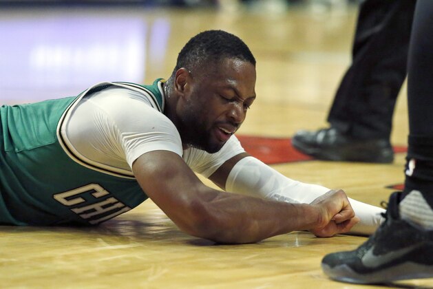 In this Wednesday, March 15, 2017 photo, Chicago Bulls guard Dwyane Wade reacts after being injured during the second half of an NBA basketball game against the Memphis Grizzlies Wednesday, March 15, 2017, in Chicago. Wade will miss the rest of the season with a fractured right elbow. (AP Photo/Nam Y. Huh)