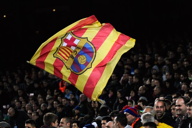 BARCELONA, SPAIN - DECEMBER 14:  A FC Barcelona supporter waves a Catalan flag with the FC Barcelona emblem during the La Liga match between FC Barcelona and Villarreal CF at Camp Nou on December 14, 2013 in Barcelona, Spain.  (Photo by David Ramos/Getty Images)