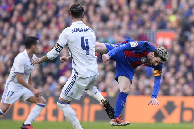 Barcelona's Argentinian forward Lionel Messi (R) falls as he vies with Real Madrid's defender Sergio Ramos during the Spanish league football match FC Barcelona vs Real Madrid CF at the Camp Nou stadium in Barcelona on December 3, 2016. / AFP / JOSEP LAGO        (Photo credit should read JOSEP LAGO/AFP/Getty Images)