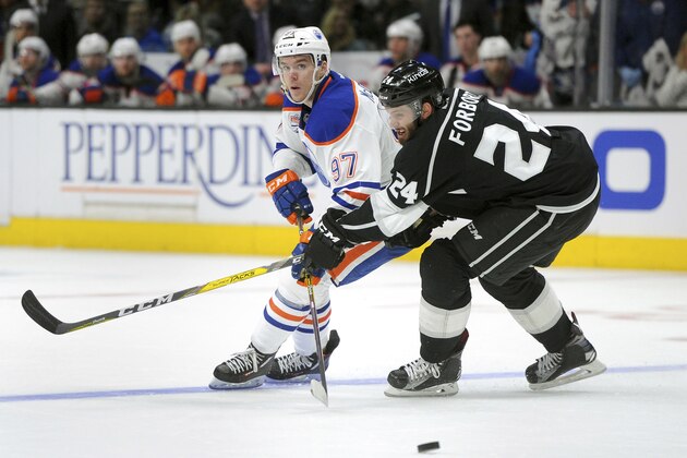 Edmonton Oilers center Connor McDavid (97) passes the puck while being pressured by Los Angeles Kings defenseman Derek Forbort (24) during an NHL hockey game, Tuesday, April 4, 2017, in Los Angeles. (AP Photo/Michael Owen Baker)