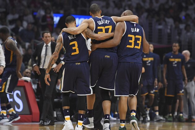 Utah Jazz center Rudy Gobert, center, is helped off the court by center Boris Diaw, right, and guard George Hill, left, as coach Quin Snyder watches after Gobert injured his knee during the first half in Game 1 of an NBA basketball first-round playoff series against the Los Angeles Clippers, Saturday, April 15, 2017, in Los Angeles. (AP Photo/Mark J. Terrill)