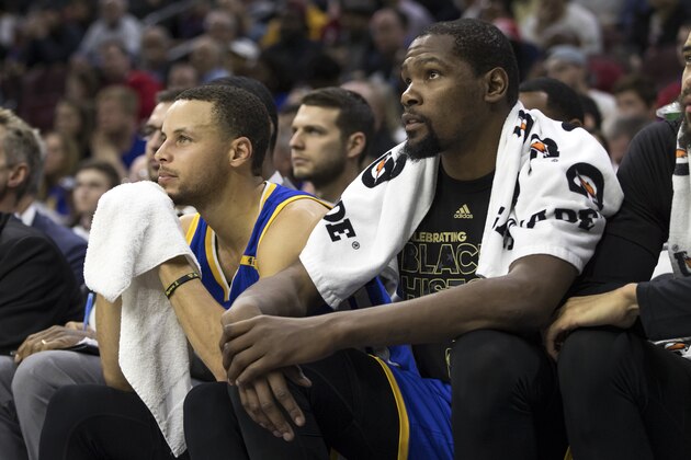 Golden State Warriors' Stephen Curry, left, looks on from the bench with Kevin Durant, right, during the second half of an NBA basketball game against the Philadelphia 76ers, Monday, Feb. 27, 2017, in Philadelphia. The Warriors won 119-108. (AP Photo/Chris Szagola)