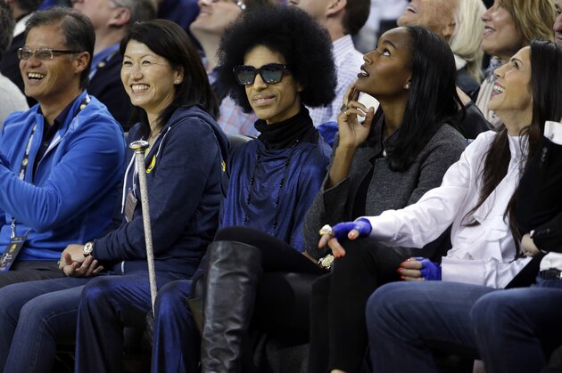 Singer Prince, center, smiles as he watches an NBA basketball game between the Golden State Warriors and the Oklahoma City Thunder Thursday, March 3, 2016, in Oakland, Calif. (AP Photo/Marcio Jose Sanchez)