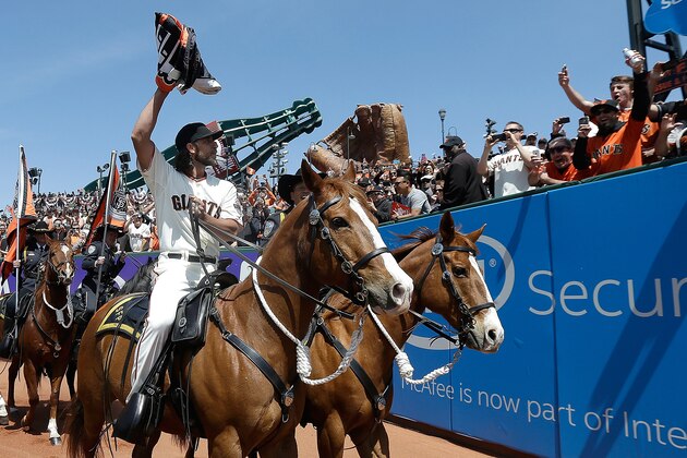SAN FRANCISCO, CA - APRIL 13:  Madison Bumgarner #40 of the San Francisco Giants riding a police horse carries the 2014 World Series Championship Flag prior to the start of their game against the Colorado Rockies on Opening Day at AT&T Park on April 13, 2015 in San Francisco, California.  (Photo by Jeff Chiu-Pool/Getty Images)