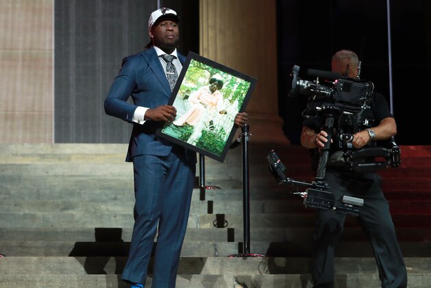 UCLA's Takkarist McKinley carries a photograph of his grandmother onstage after being selected by the Atlanta Falcons during the first round of the 2017 NFL football draft, Thursday, April 27, 2017, in Philadelphia.(Jeff Haynes/AP Images for Panini)