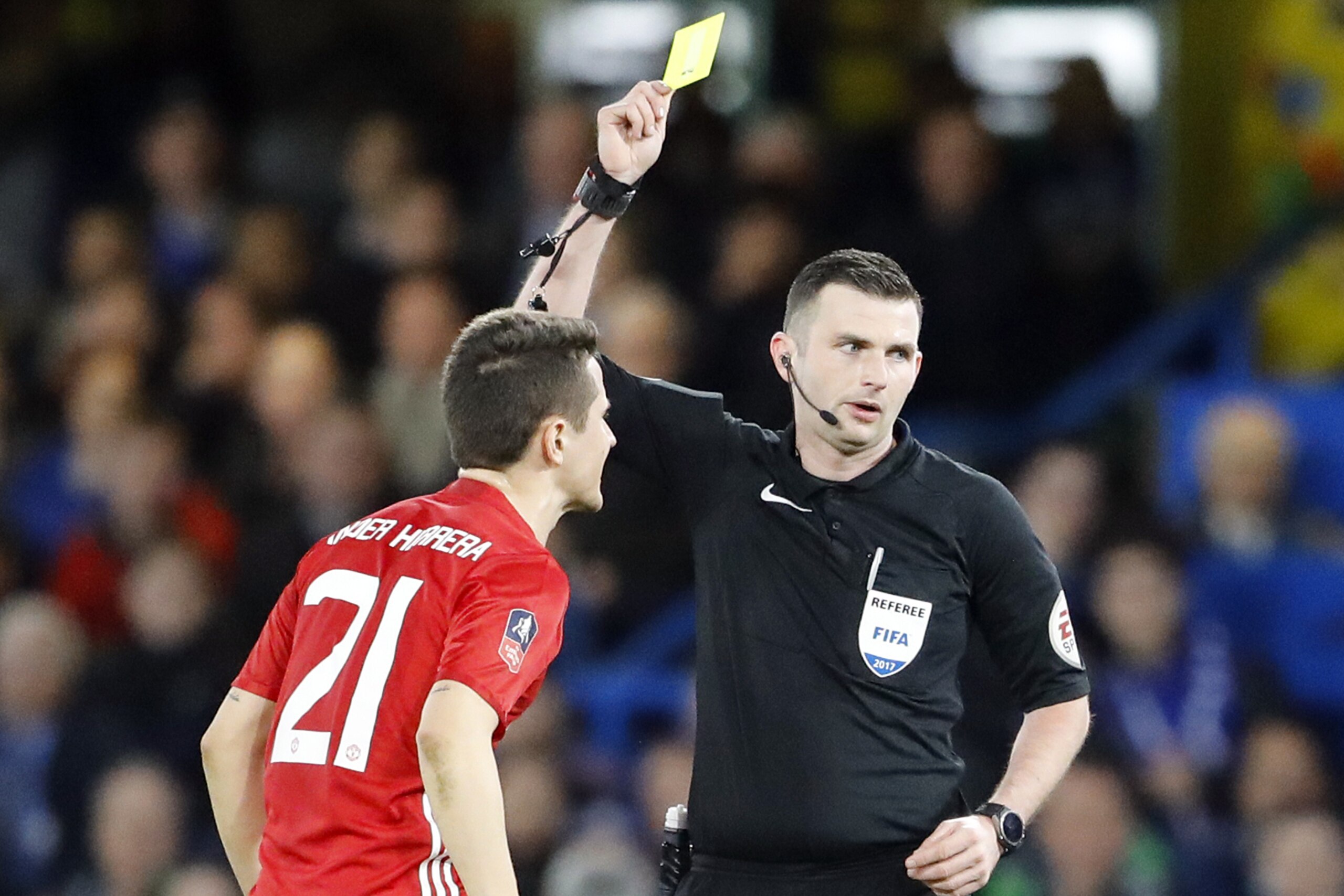 Referee Michael Oliver shows a yellow card to United's Ander Herrera, left, during the English FA Cup quarterfinal soccer match between Chelsea and Manchester United at Stamford Bridge stadium in London, Monday, March 13, 2017. (AP Photo/Frank Augstein)