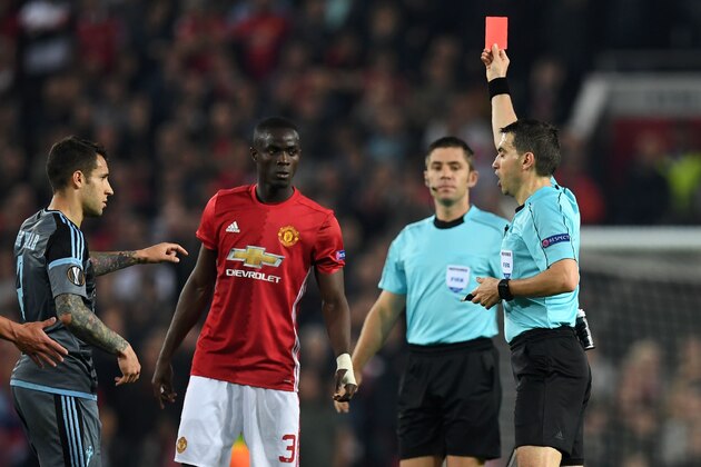 Romanian referee Ovidiu Hategan (R) shows a red card to Manchester United's Ivorian defender Eric Bailly (C), after a clash between players during the UEFA Europa League semi-final, second-leg football match between Manchester United and Celta Vigo at Old Trafford stadium in Manchester, north-west England, on May 11, 2017. / AFP PHOTO / Paul ELLIS        (Photo credit should read PAUL ELLIS/AFP/Getty Images)