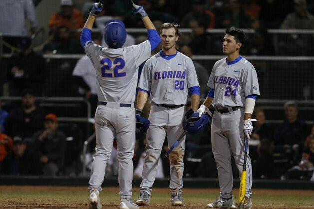CORAL GABLES, FL - FEBRUARY 26: JJ Schwarz #22 is congratulated by Peter Alonso #20 and Jeremy Vasquez #24 of the Florida Gators after hitting a solo home run against the Miami Hurricanes on February 26, 2016 at Alex Rodriguez Park at Mark Light Field in Coral Gables, Florida. Florida defeated Miami 5-0. (Photo by Joel Auerbach/Getty Images)