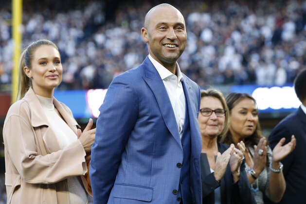 Retired New York Yankees shortstop Derek Jeter, center, his wife Hannah Jeter, left, his mother Dorothy and sister Sharlee are shown on the field during a pregame ceremony retiring his number 2 in Monument Park at Yankee Stadium in New York, Sunday, May 14, 2017. (AP Photo/Pool, Kathy Willens)