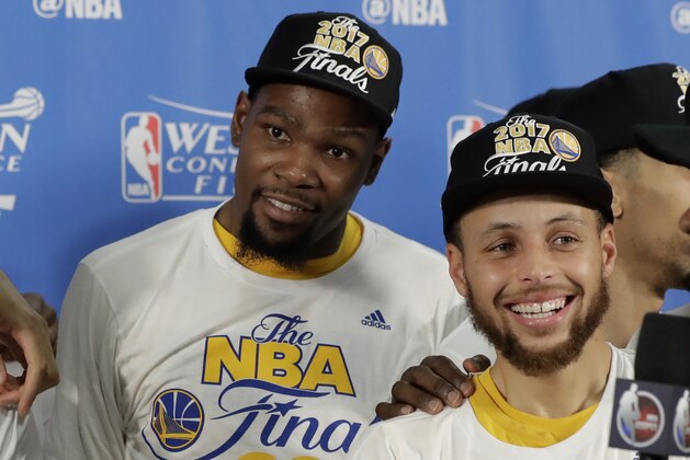 Golden State Warriors' Kevin Durant, left, and Stephen Curry, right, stand on stage by the trophy after beating the San Antonio Spurs 129-115 in Game 4 of the NBA basketball Western Conference finals, Monday, May 22, 2017, in San Antonio. (AP Photo/Eric Gay)