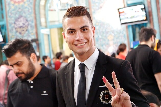 Iranian Reza Alireza Lou, a look-alike of Real Madrid's Portuguese soccer player Cristiano Ronaldo, holds his ID card as he poses for photographs during the Iranian presidential elections on May 19, 2017 at a polling station in Tehran.  / AFP PHOTO / STR        (Photo credit should read STR/AFP/Getty Images)