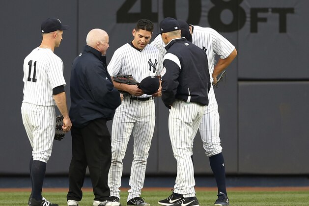 New York Yankees left fielder Brett Gardner (11), Yankees trainer Steve Donohue, Yankees manager Joe Girardi and right fielder Aaron Judge gather around Yankees center fielder Jacoby Ellsbury, third from left, after Ellsbury collided with the outfield wall fielding a flyout by Kansas City Royals' Alcidies Escobar during the first inning of a baseball game at Yankee Stadium in New York, Wednesday, May 24, 2017. The Yankees placed Ellsbury on the seven day DL after the game. (AP Photo/Kathy Willens)