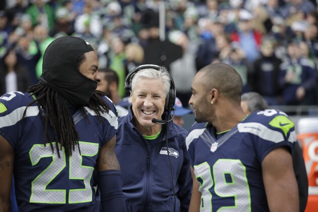 Seattle Seahawks head coach Pete Carroll, center, throws his arms around Richard Sherman (25) and Doug Baldwin before an NFL football game against the Arizona Cardinals, Sunday, Nov. 23, 2014, in Seattle. (AP Photo/Elaine Thompson)
