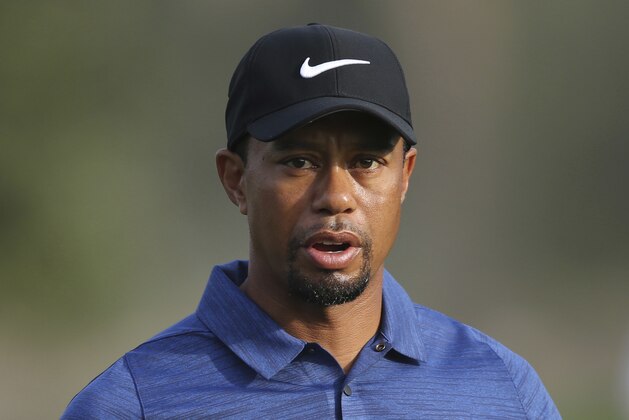 In this Thursday, Feb. 2, 2017 photo, Tiger Woods reacts on hole 10th during the 1st round of the Dubai Desert Classic golf tournament in Dubai, United Arab Emirates. Tiger Woods has withdrawn from the Dubai Desert Classic with an apparent back injury after shooting an opening-round 5-over 77. (AP Photo/Kamran Jebreili)
