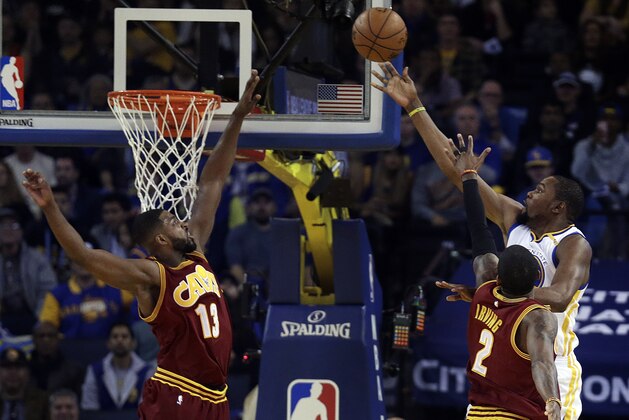 Golden State Warriors' Kevin Durant, right, lays up a shot against Cleveland Cavaliers' Tristan Thompson, left, and Kyrie Irving (2) during the first half of an NBA basketball game Monday, Jan. 16, 2017, in Oakland, Calif. (AP Photo/Ben Margot)
