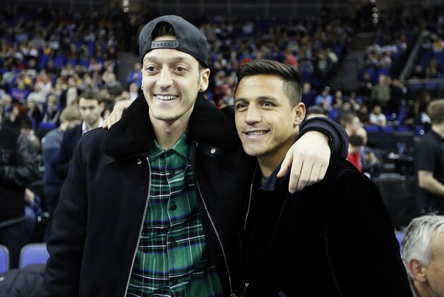 Arsenal soccer players Mesut Ozil, left, and Alexis Sanchez watch the NBA basketball match between Indiana Pacers and Denver Nuggets in London, Thursday, Jan. 12, 2017.(AP Photo/Kirsty Wigglesworth)