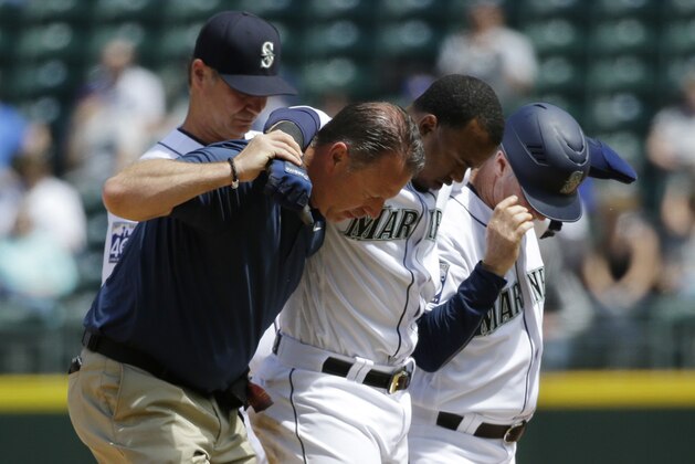 Seattle Mariners' Jean Segura, third from left, is helped off the field by trainer Rob Nodine, left, and first base coach Casey Candaele, right, after suffering an injury sliding into second base in the fourth inning of a baseball game against the Colorado Rockies, Thursday, June 1, 2017, in Seattle. Segura was out on the play and left the game. (AP Photo/Ted S. Warren)