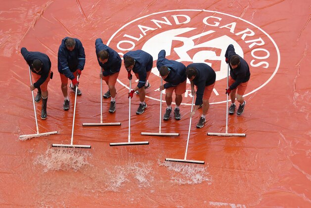 PARIS, FRANCE - JUNE 06: Groundsmen clear the court after rain stopped play at the Suzanne Lenglen Court during the match between Jelena Ostapenko of Latvia and Caroline Wozniacki of Denmark, on day ten at Roland Garros on June 6, 2017 in Paris, France. (Photo by Ian MacNicol/Getty Images)