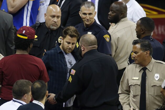 A fan, center left, is removed from the audience near the Golden State Warriors' bench in the second half of Game 4 of basketball's NBA Finals between the Warriors and the Cleveland Cavaliers in Cleveland, Friday, June 9, 2017. (AP Photo/Ron Schwane)