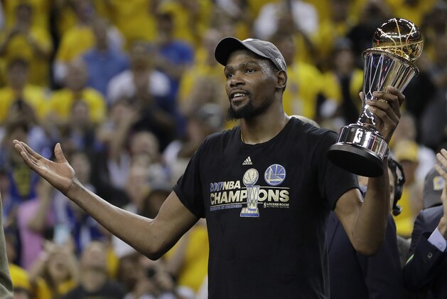 Golden State Warriors forward Kevin Durant gestures as he holds the Bill Russell NBA Finals Most Valuable Player Award after Game 5 of basketball's NBA Finals between the Warriors and the Cleveland Cavaliers in Oakland, Calif., Monday, June 12, 2017. The Warriors won 129-120 to win the NBA championship. (AP Photo/Marcio Jose Sanchez)