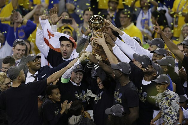 Golden State Warriors players, coaches and owners hold up the Larry O'Brien NBA Championship Trophy after Game 5 of basketball's NBA Finals between the Warriors and the Cleveland Cavaliers in Oakland, Calif., Monday, June 12, 2017. The Warriors won 129-120 to win the NBA championship. (AP Photo/Ben Margot)
