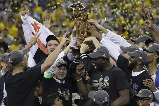 Golden State Warriors players, coaches and owners hold up the Larry O'Brien NBA Championship Trophy after Game 5 of basketball's NBA Finals between the Warriors and the Cleveland Cavaliers in Oakland, Calif., Monday, June 12, 2017. The Warriors won 129-120 to win the NBA championship. (AP Photo/Marcio Jose Sanchez)