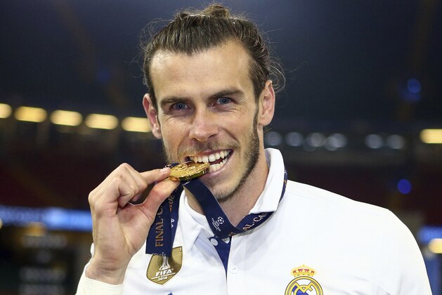 Real Madrid's Gareth Bale bites his winners medal at the end of the Champions League soccer final between Juventus and Real Madrid at the Millennium Stadium in Cardiff, Wales, Saturday, June 3, 2017. Real won the match 4-1. (AP Photo/Frank Augstein)