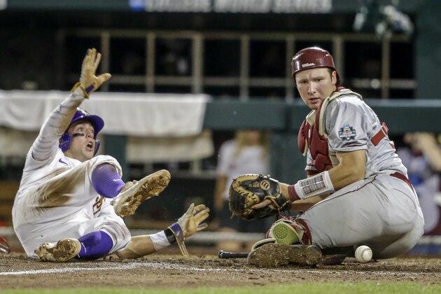 LSU's Cole Freeman, left, scores at home plate after Florida State catcher Cal Raleigh (35) couldn't hold on to the ball during the eighth inning of an NCAA College World Series baseball game in Omaha, Neb., Saturday, June 17, 2017. LSU won 5-4. (AP Photo/Nati Harnik)
