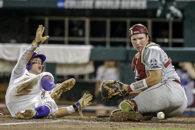 LSU's Cole Freeman, left, scores at home plate after Florida State catcher Cal Raleigh (35) couldn't hold on to the ball during the eighth inning of an NCAA College World Series baseball game in Omaha, Neb., Saturday, June 17, 2017. LSU won 5-4. (AP Photo/Nati Harnik)